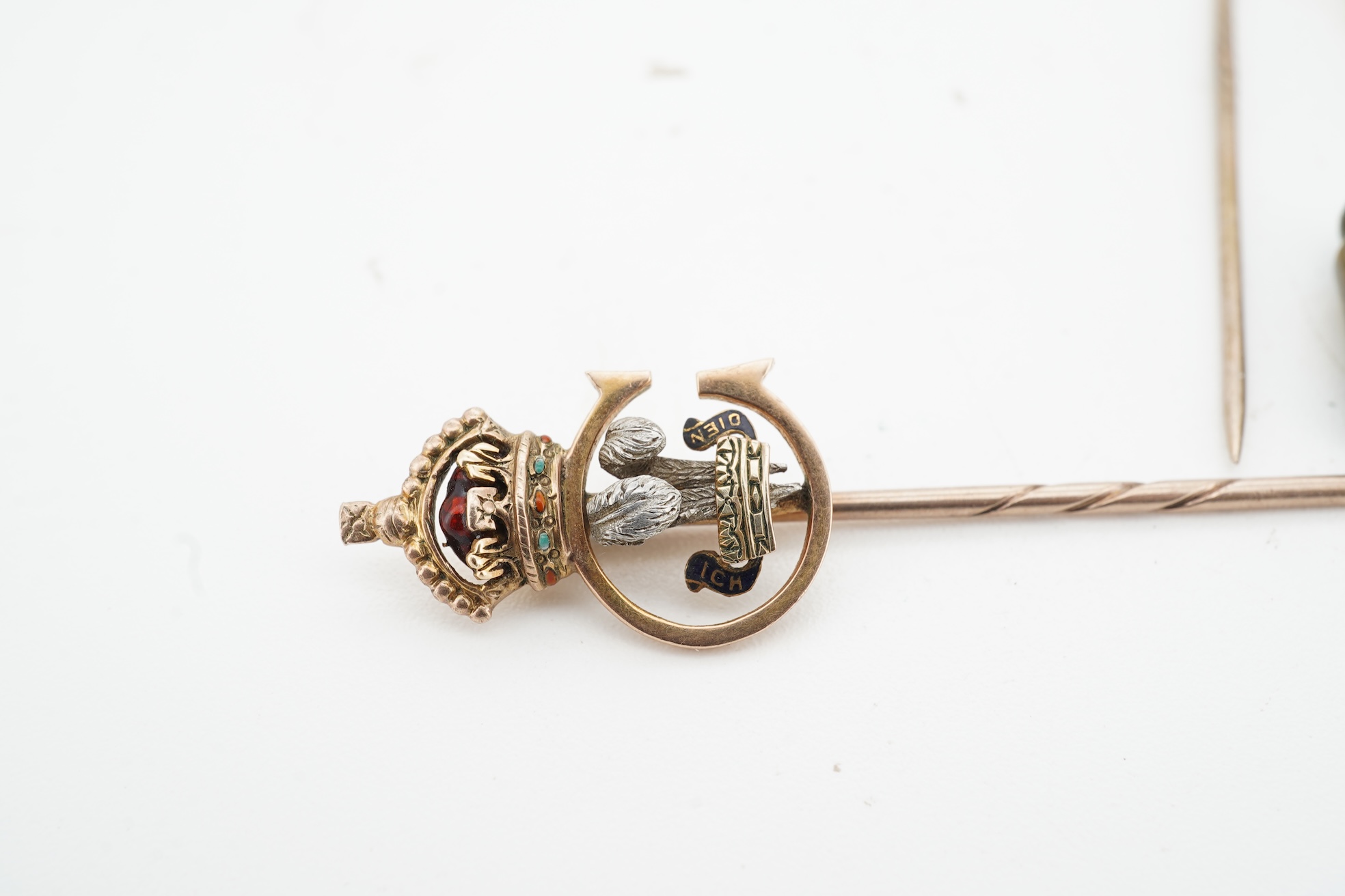 A collection of jewels, comprising: a stick pin, capped with the 'C' cipher with crowned ostrich feather and 'Ich Dien' motto for King Charles when Prince of Wales, in varicoloured gold and enamel, length 6.9cm, gross we